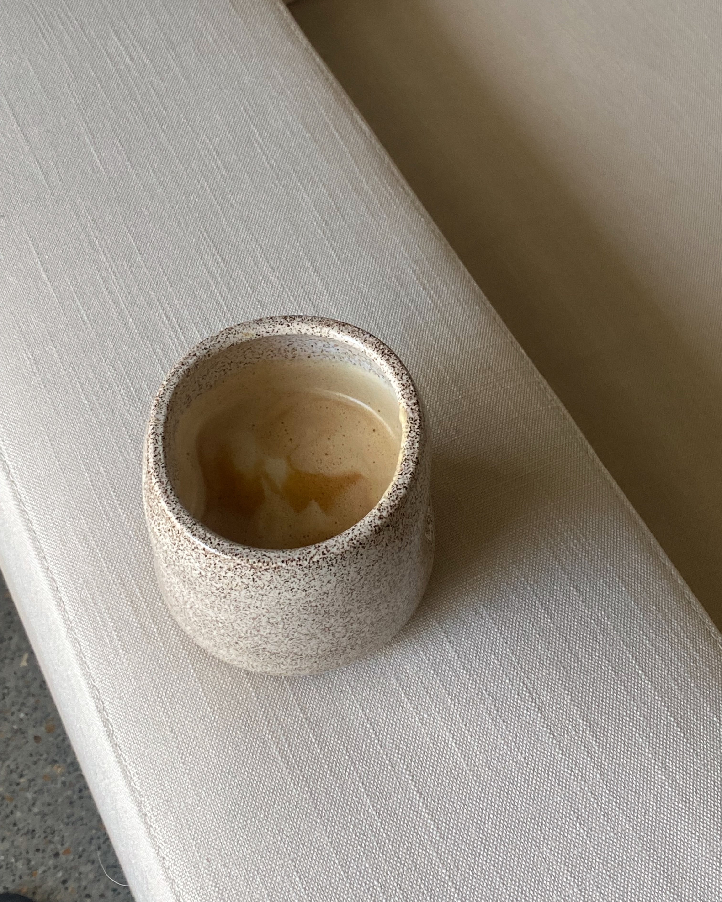 Small ceramic cup with textured exterior on a light surface