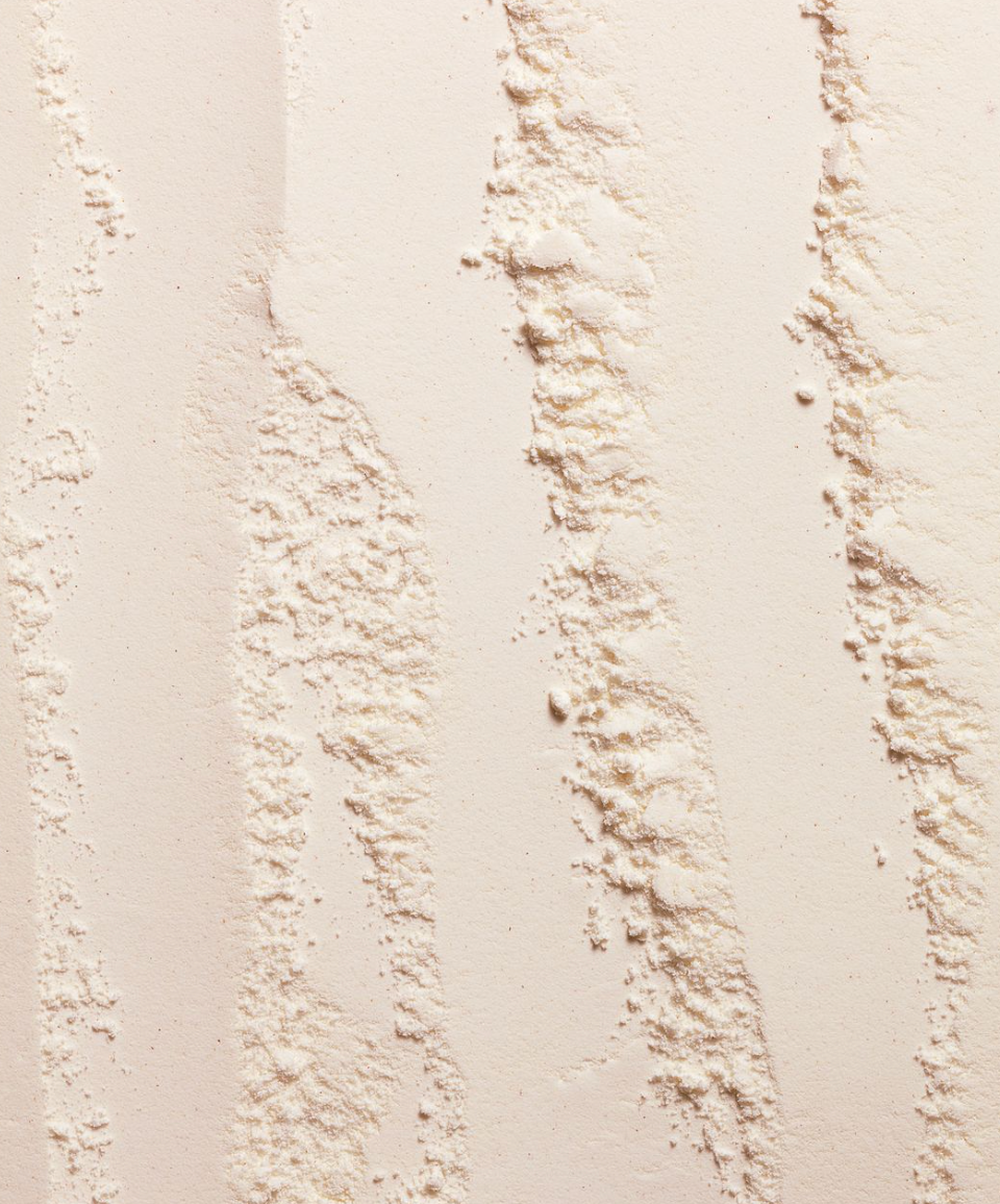 Close-up of a textured beige powder surface with wavy patterns