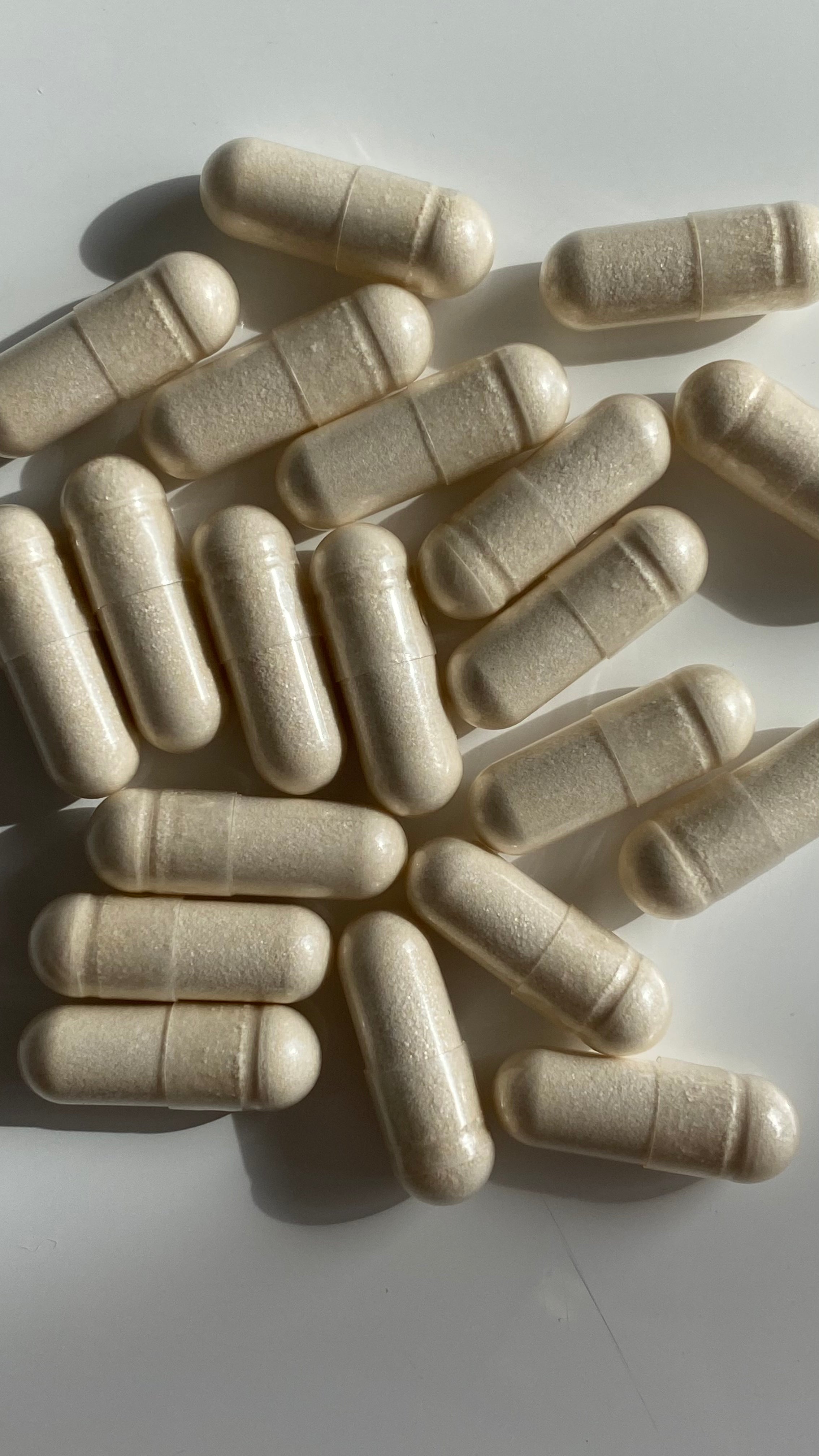 Beige capsules scattered on a white surface
