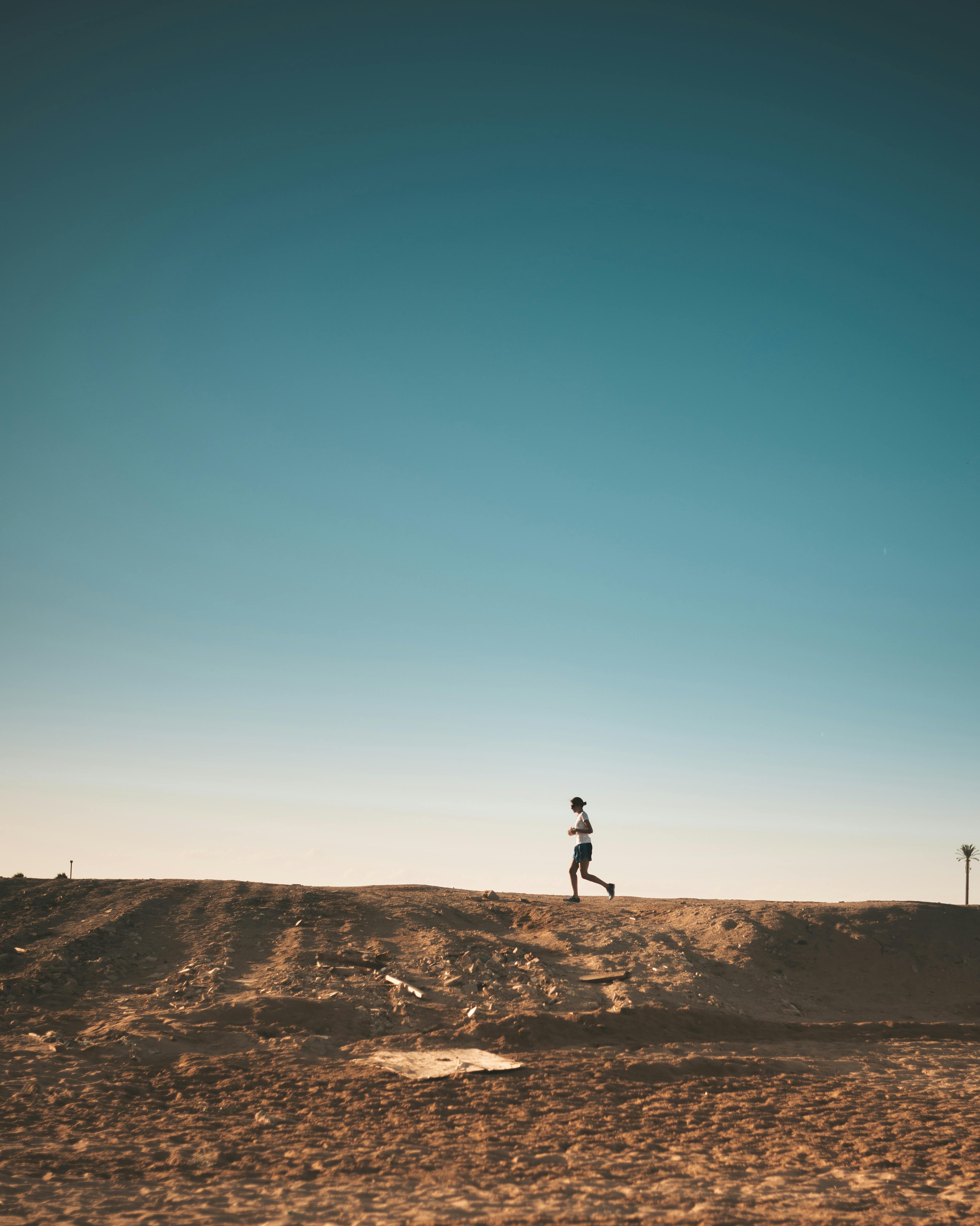 woman running in desert with a blue sky 