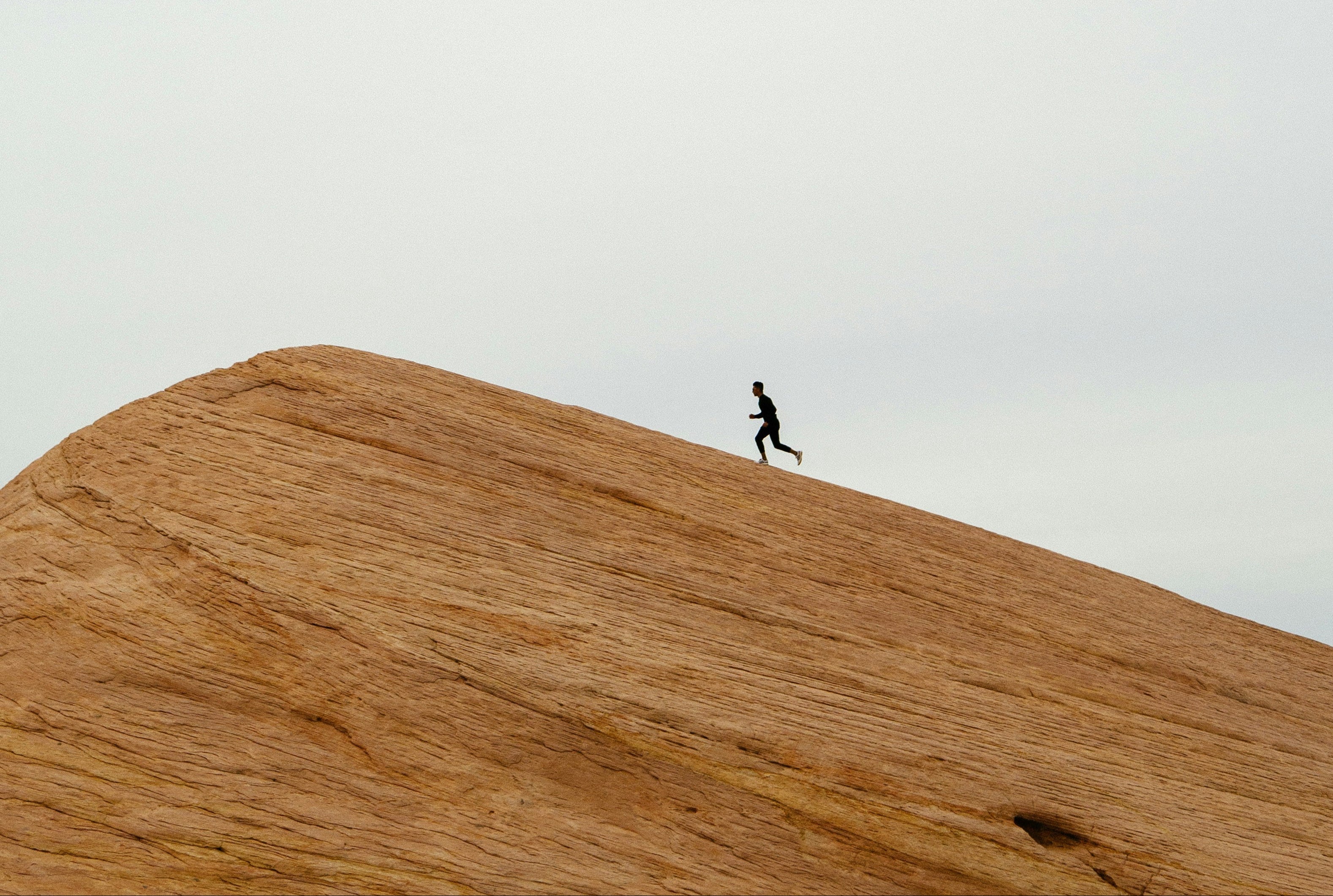 Person running on a sand dune with a minimalistic background