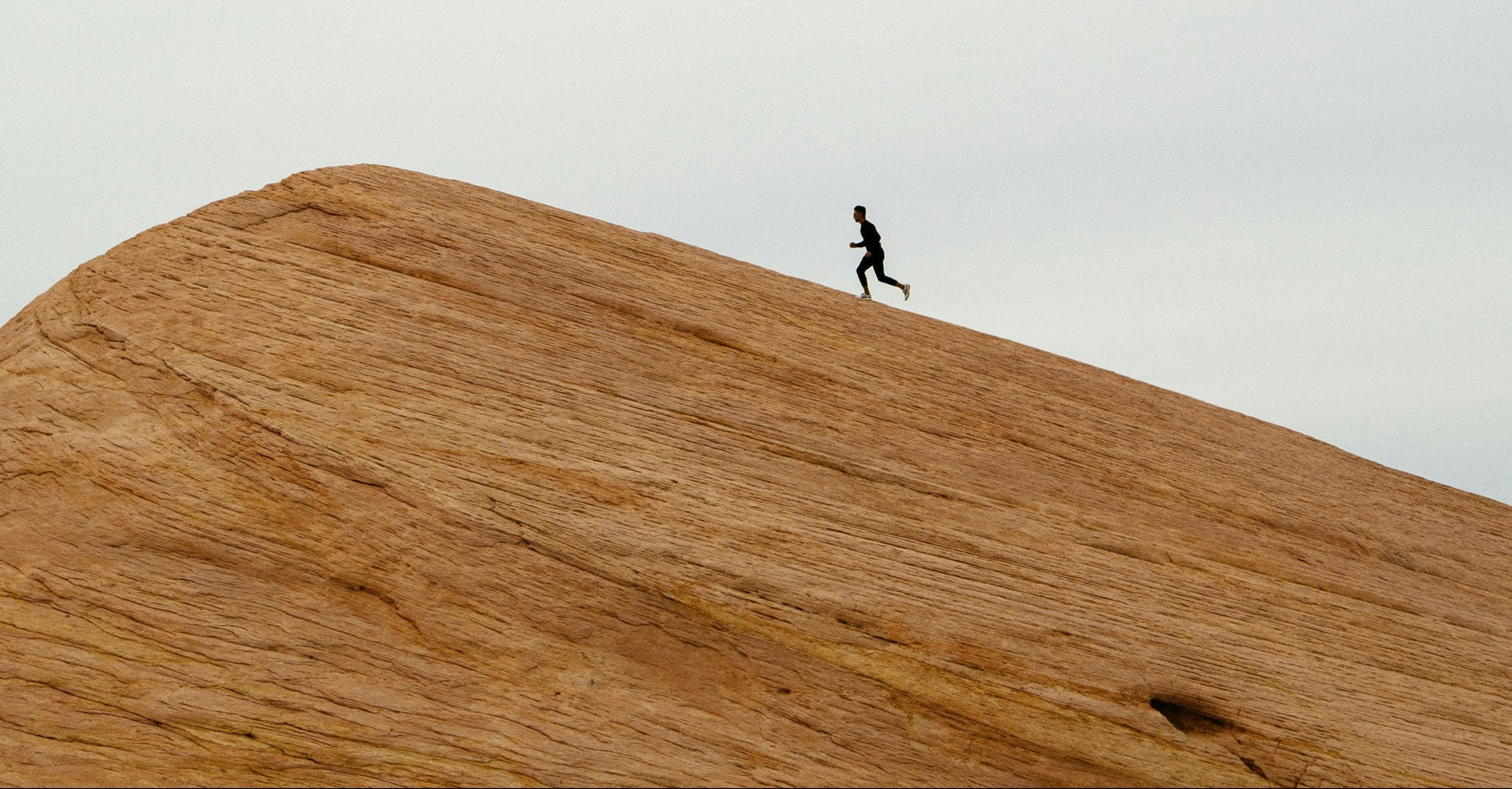 Person running on a sand dune with a minimalistic background