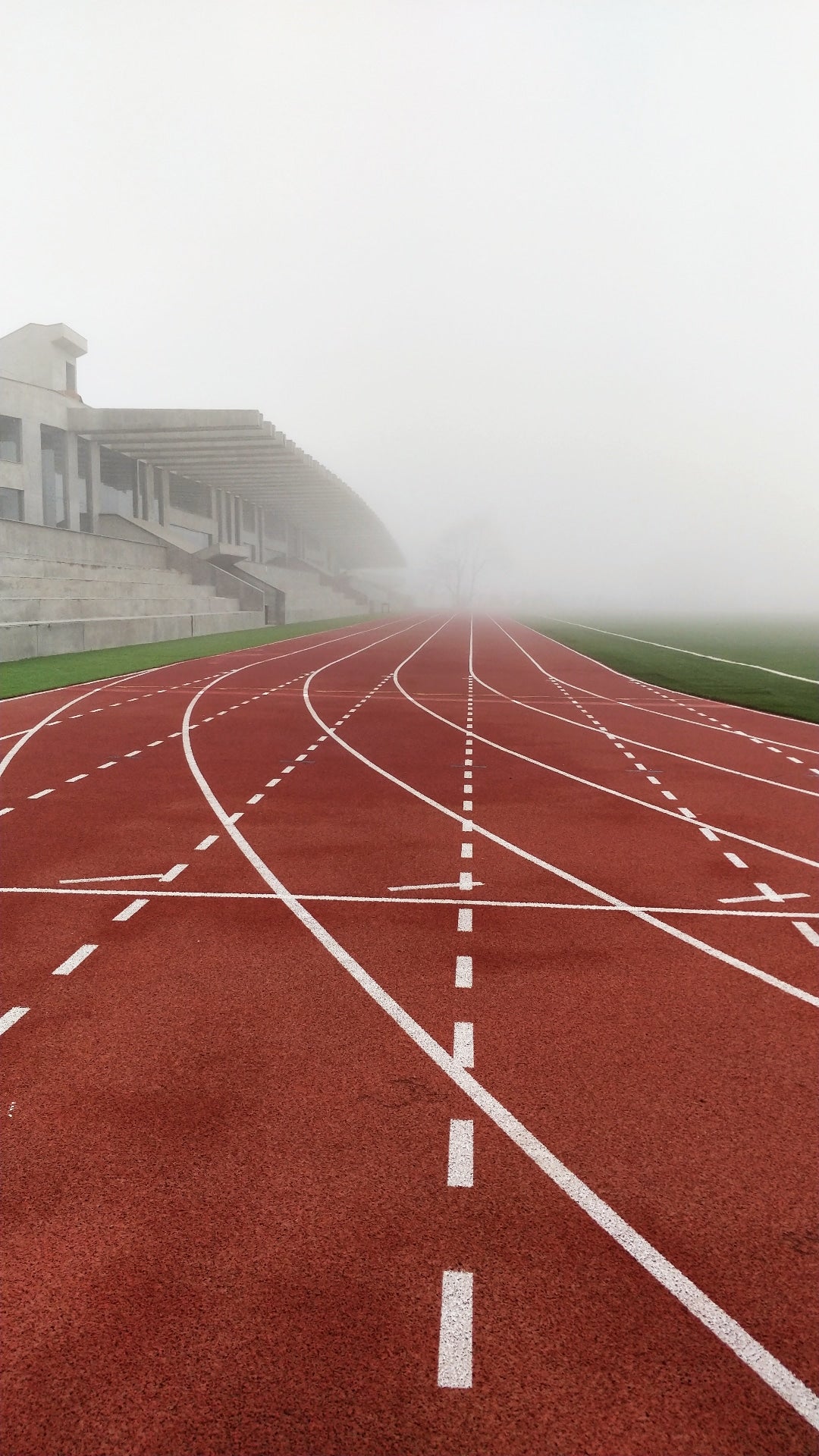 Running track with white lanes on a foggy day