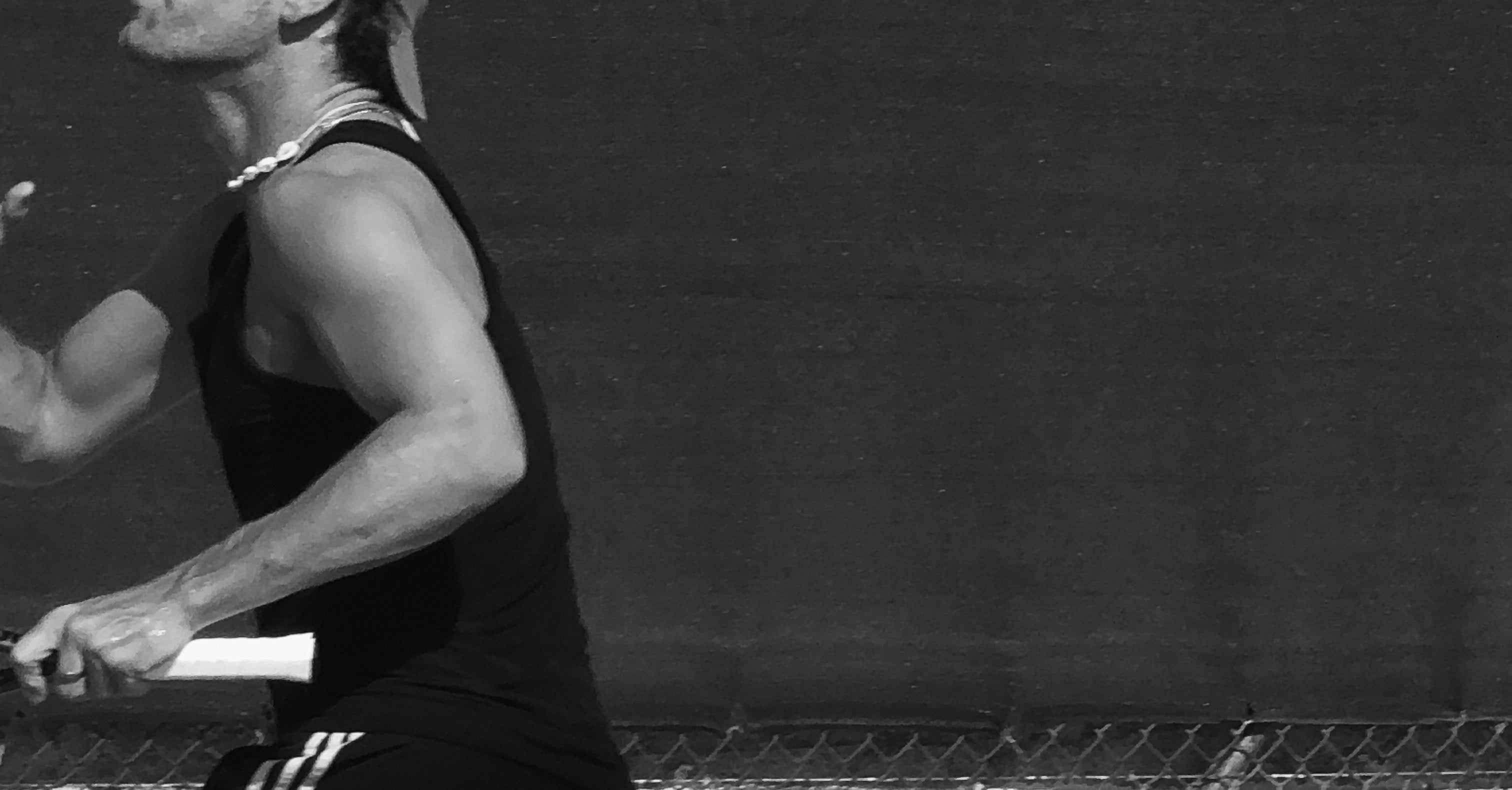 Person playing tennis with a racket against a dark background